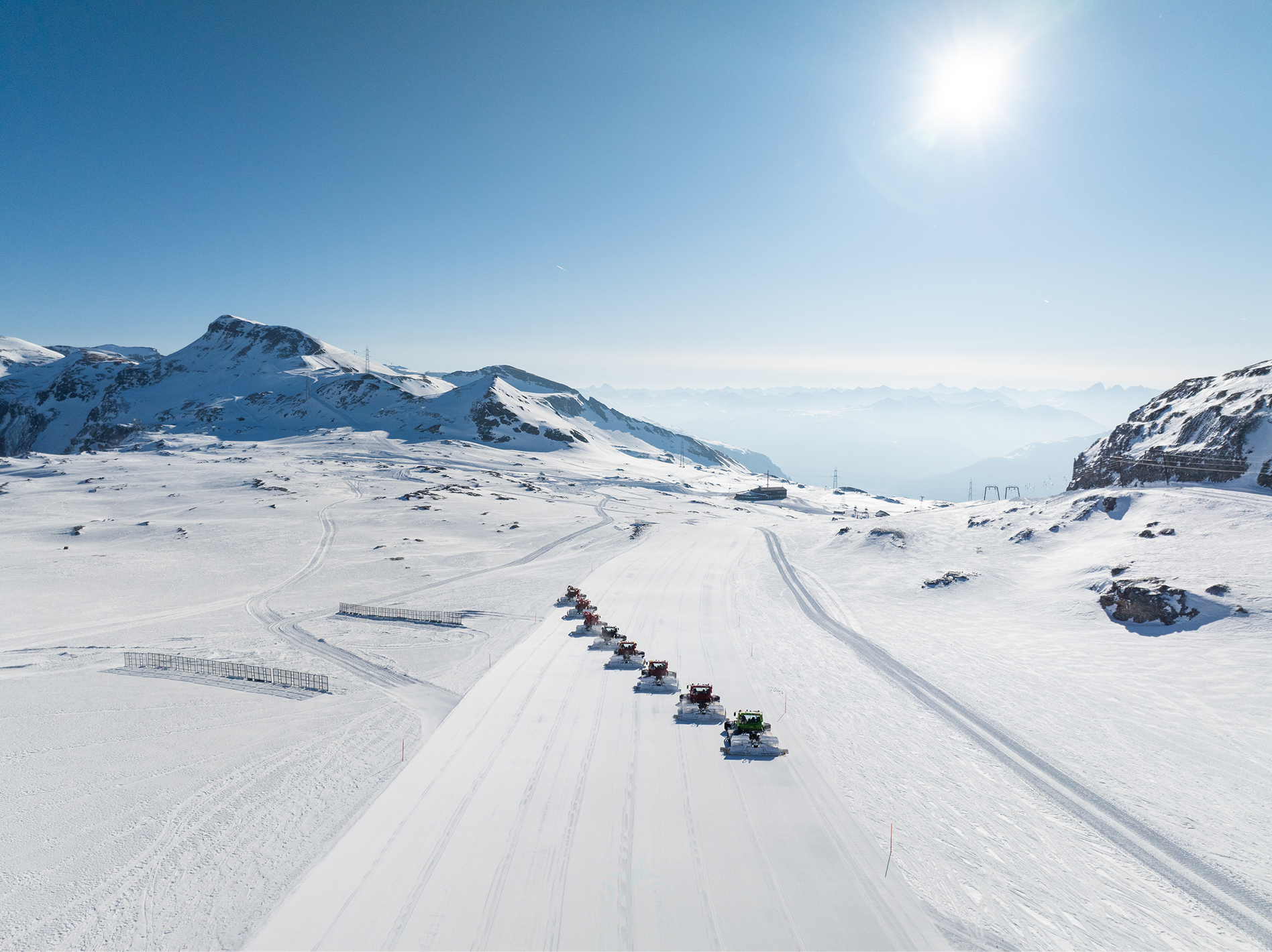 Luftaufnahme eines Gletscherskigebiets mit einer Kolonne Pistenraupen