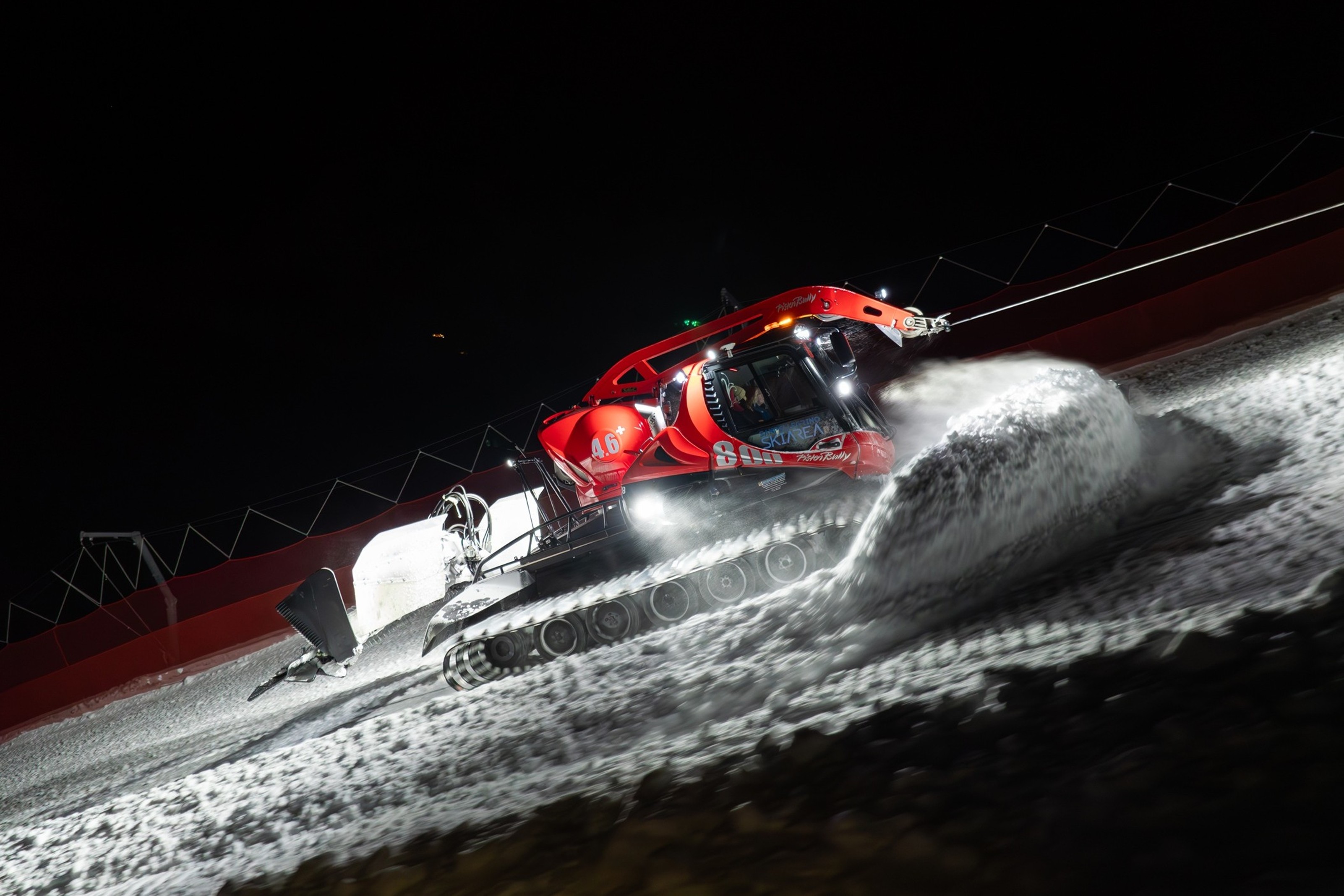 Pistenraupe bei Nacht im eigenen Scheinwerferlicht auf der Piste