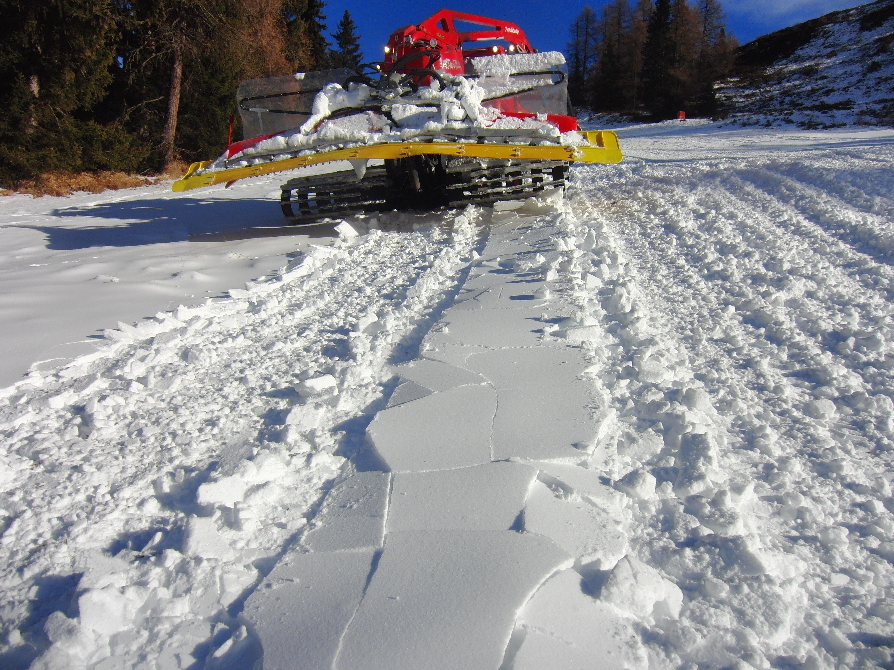 Pistenraupe von hinten auf frisch präparierter Piste mit sichtbarem Fräsmuster